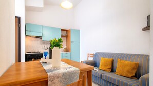 Un espacio habitable compacto con una mesa de comedor, un sofá y una kitchenette.