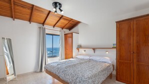 Un dormitorio con cama, armario de madera y vista al mar.
