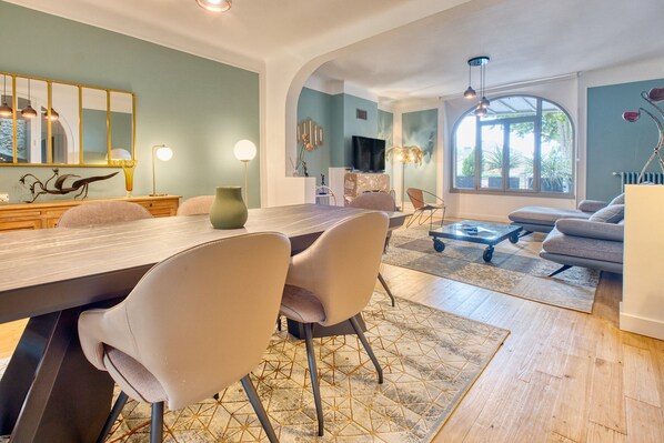 A modern living room with a dining area, a large window, and a television.