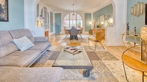 A spacious living room with a sofa, coffee table, and chairs, an archway leading to a dining area, and a view through the archway. - Guest House 'La Chambre Bleue' with Shared Terrace, Shared Garden and Wi-Fi (Eymet)