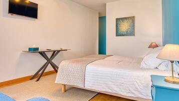 A bedroom with a bed, a desk, a TV, and a lamp.