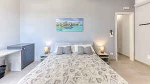 Un dormitorio con cama, mesitas de noche, un escritorio y un cuadro en la pared.