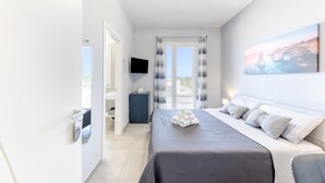 Una habitación de hotel con cama, televisión, balcón con cortinas y un cuadro en la pared.