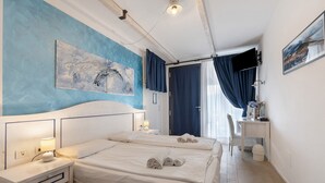 Una camera d'albergo con un letto, comodini, una scrivania, una sedia e opere d'arte alle pareti.