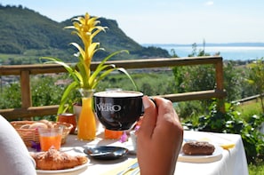 Un tavolo con prodotti per la colazione, una tazza di caffè e vista sul paesaggio costiero.