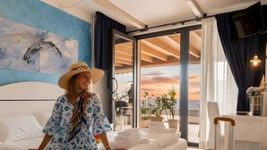 Una stanza con un letto, una valigia, un quadro e vista attraverso una porta in vetro.