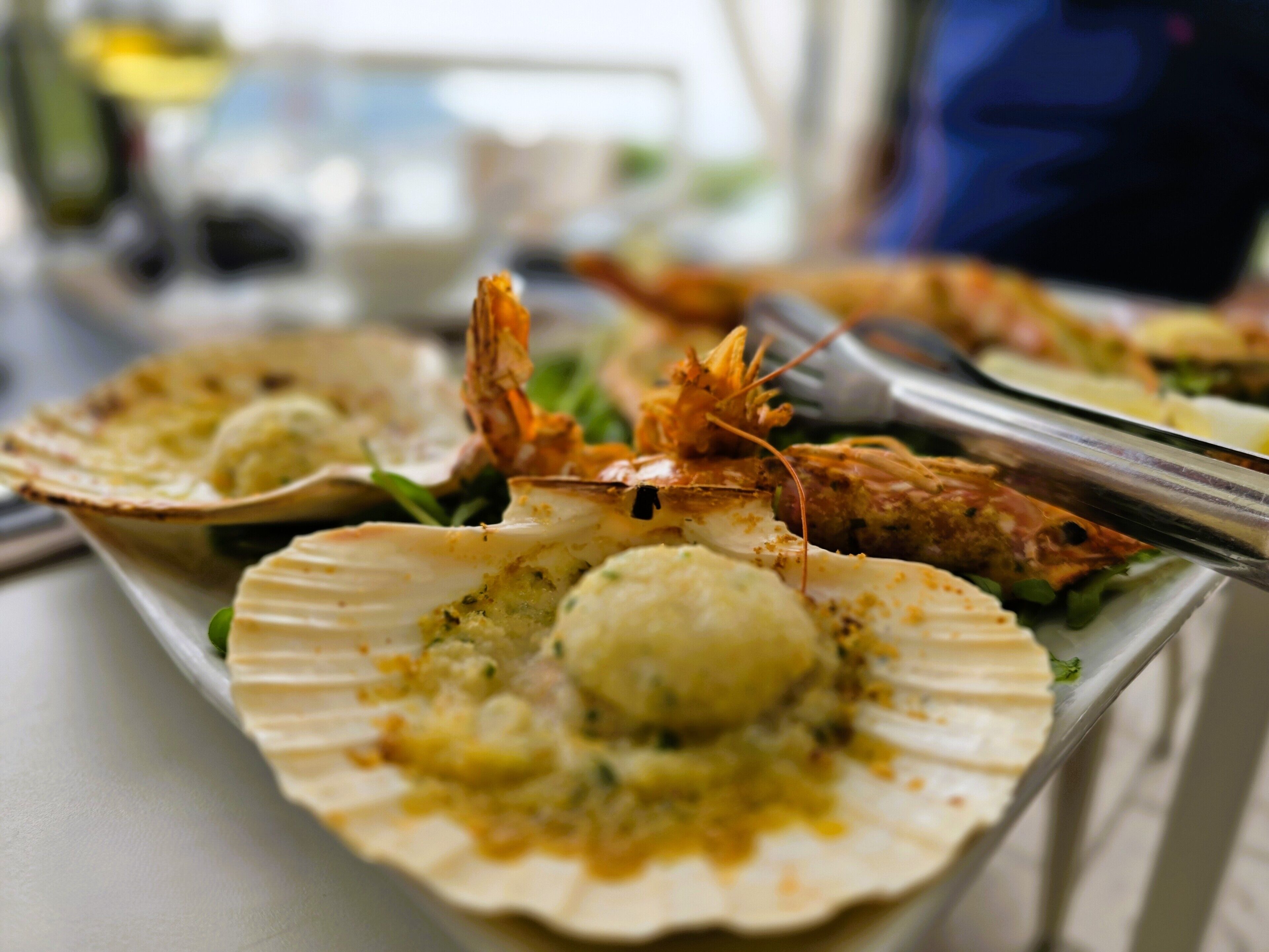 Un plat de fruits de mer composé de noix de Saint-Jacques et de crevettes, présenté sur une assiette.