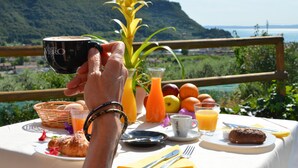 Une table de petit-déjeuner avec un croissant, un jus de fruits et une tasse de café, le tout mis en valeur par un magnifique paysage de montagne en arrière-plan.
