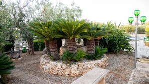Um jardim com plantas verdes exuberantes, um banco de pedra e um poste de luz.