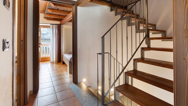Eine Treppe mit Holzboden und Metallgeländern, die zu einer oberen Etage führt.