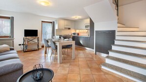 Eine moderne Wohnung mit Essbereich, Küche, Wohnzimmer und Treppe.