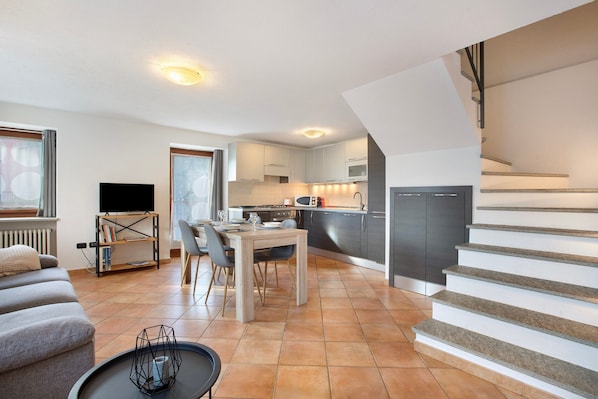A modern apartment with a dining area, kitchen, living room, and staircase.