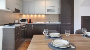 Eine moderne Küche mit Edelstahlgeräten, einem Esstisch für vier Personen und einem dunklen Holzschrank.