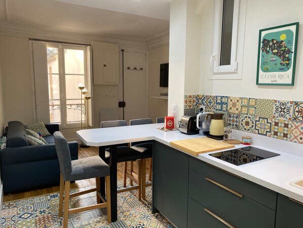 A compact kitchen with a dining area, a sofa, and a tiled backsplash.