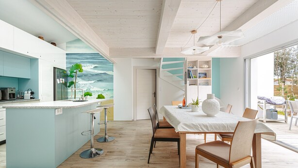 A modern kitchen with a central island, a dining area with a table and chairs, and a view of the outdoors. - Architect's Villa 800m from the Sea – Comfort, Nature, and Serenity in Oléron, with Terrace Garden (Dolus-d'Oleron)