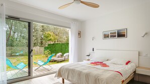 A bedroom with a bed, a ceiling fan, a sliding glass door to a patio, and a framed picture on the wall. - Architect's Villa 800m from the Sea – Comfort, Nature, and Serenity in Oléron, with Terrace Garden (Dolus-d'Oleron)