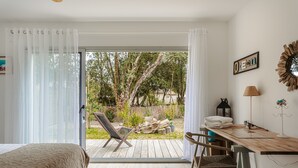 A bedroom with a bed, a wooden desk, a chair, a window with sheer curtains, and a view of the outdoors. - Architect's Villa 800m from the Sea – Comfort, Nature, and Serenity in Oléron, with Terrace Garden (Dolus-d'Oleron)