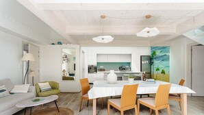 A modern living room with a dining table, chairs, a sofa, and a kitchen in the background. - Architect's Villa 800m from the Sea – Comfort, Nature, and Serenity in Oléron, with Terrace Garden (Dolus-d'Oleron)