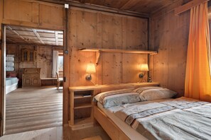 Ein Schlafzimmer einer Holzhütte mit einem Bett, Nachttischlampen und einem Holztisch.