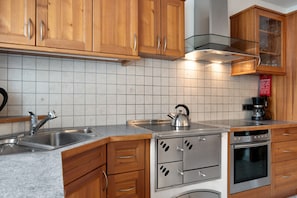 A kitchen with wooden cabinets, a stainless steel stove, a kettle, and a coffee maker.
