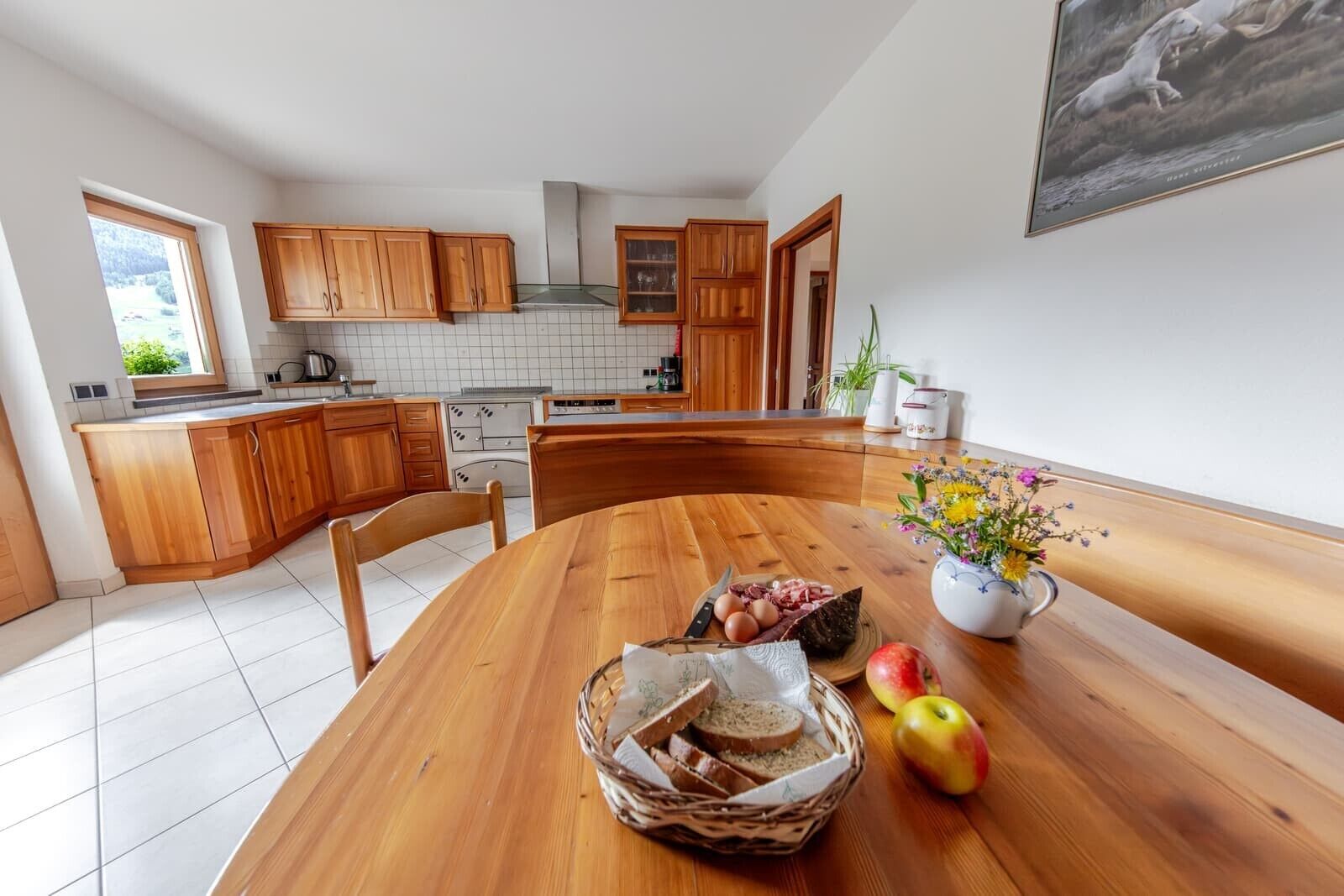 Una cocina con armarios de madera, una mesa de comedor con un florero y vistas al exterior.