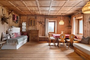 A wooden cabin interior with a dining area, a sofa, and a fireplace.