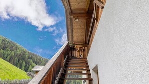 Een houten balkon met uitzicht op een bebost heuvel.’