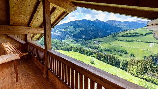Een houten balkon met uitzicht op een bergachtig landschap.