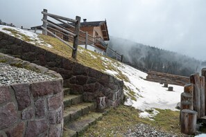 A stone staircase leading to a wooden building with a view of a forested mountain.