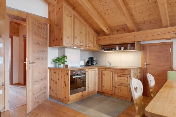 Une cuisine en bois, avec des placards, une cuisinière et un évier.