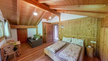 Una cabaña de madera con un dormitorio en la buhardilla, una pequeña zona de estar y techo de madera.