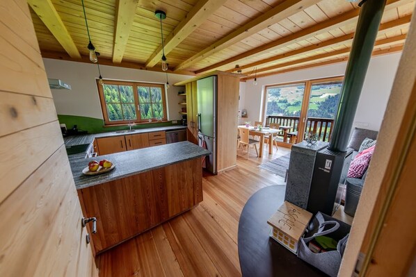 L’intérieur d’un chalet en bois comprend une cuisine, un coin repas et une cheminée.