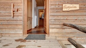 A wooden cabin interior with a wooden door, a sign reading 'Almhütte,' and a visible kitchen area. - Chalet "Almhütte" with Mountain Views, Private Terrace, and Wi-Fi (Sarentino)
