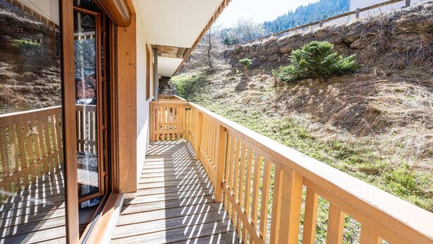 Un balcon en bois offrant une vue sur une colline.