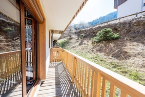 A wooden balcony with a view of a hillside.