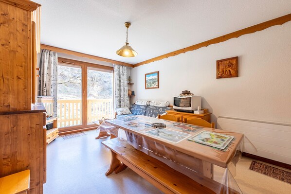 A cozy room with a wooden bench, a table with a map, a television, and a window with curtains.