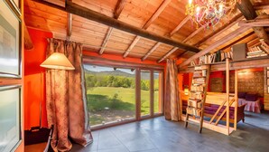 Ein Zimmer mit großem Fenster, Holzbalkendecke, einer Chandelier und einem Bücherregal.