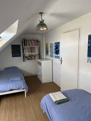 Una camera da letto con due letti, una scrivania, una libreria e un ventilatore a soffitto.