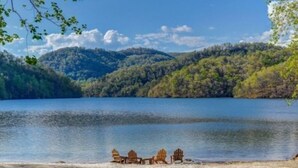 Une vue sur le lac, avec une rangée de fauteuils Adirondack disposés sur la rive.