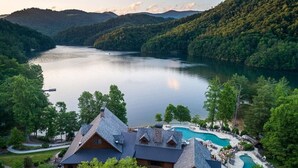 Un chalet doté d’une grande piscine, entouré d’une végétation luxuriante et bordé d’un lac.