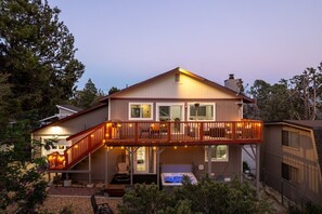 A two-story house with a balcony, outdoor seating, and a hot tub.