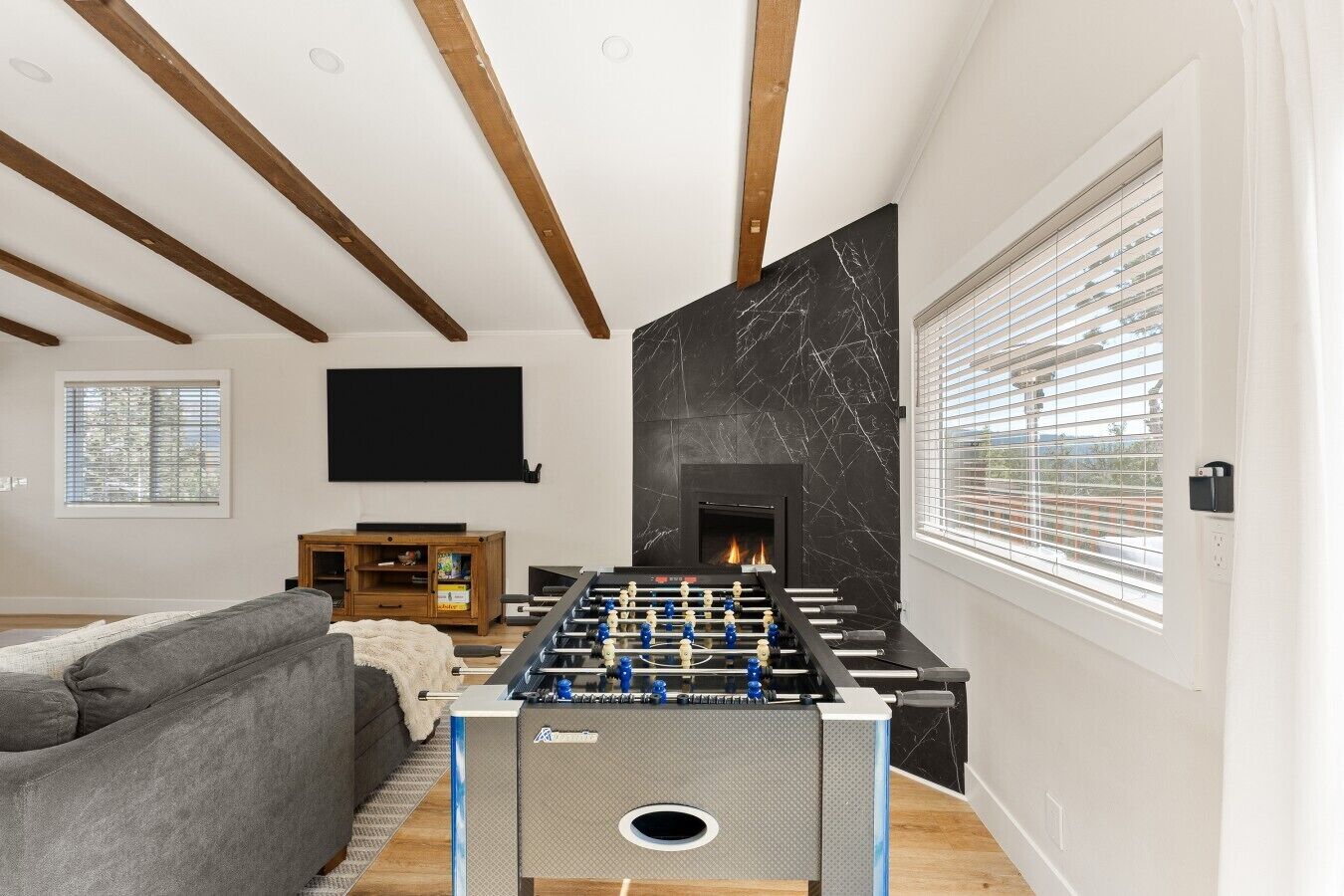 A living room with a foosball table, a fireplace, a mounted TV, and a sofa.