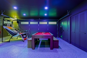 A room with a pool table, a trampoline, and a basketball hoop.