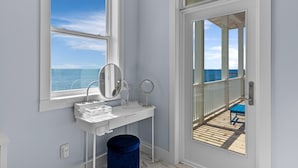 Un baño con tocador, un ventanal y vista al océano.