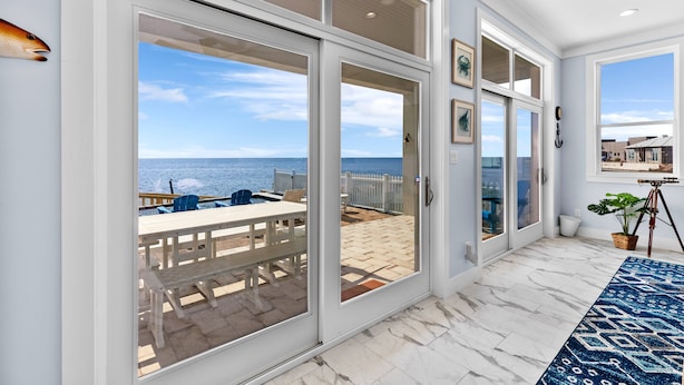 Una habitación con un amplio ventanal corredera que da a un patio con vista al mar.