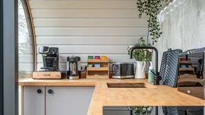 Una kitchenette compacta con cafetera, tostadora y estantes de almacenamiento.
