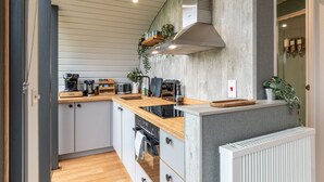 Una cocina compacta con encimera de madera, electrodomésticos integrados y una pared de detalles de hormigón.