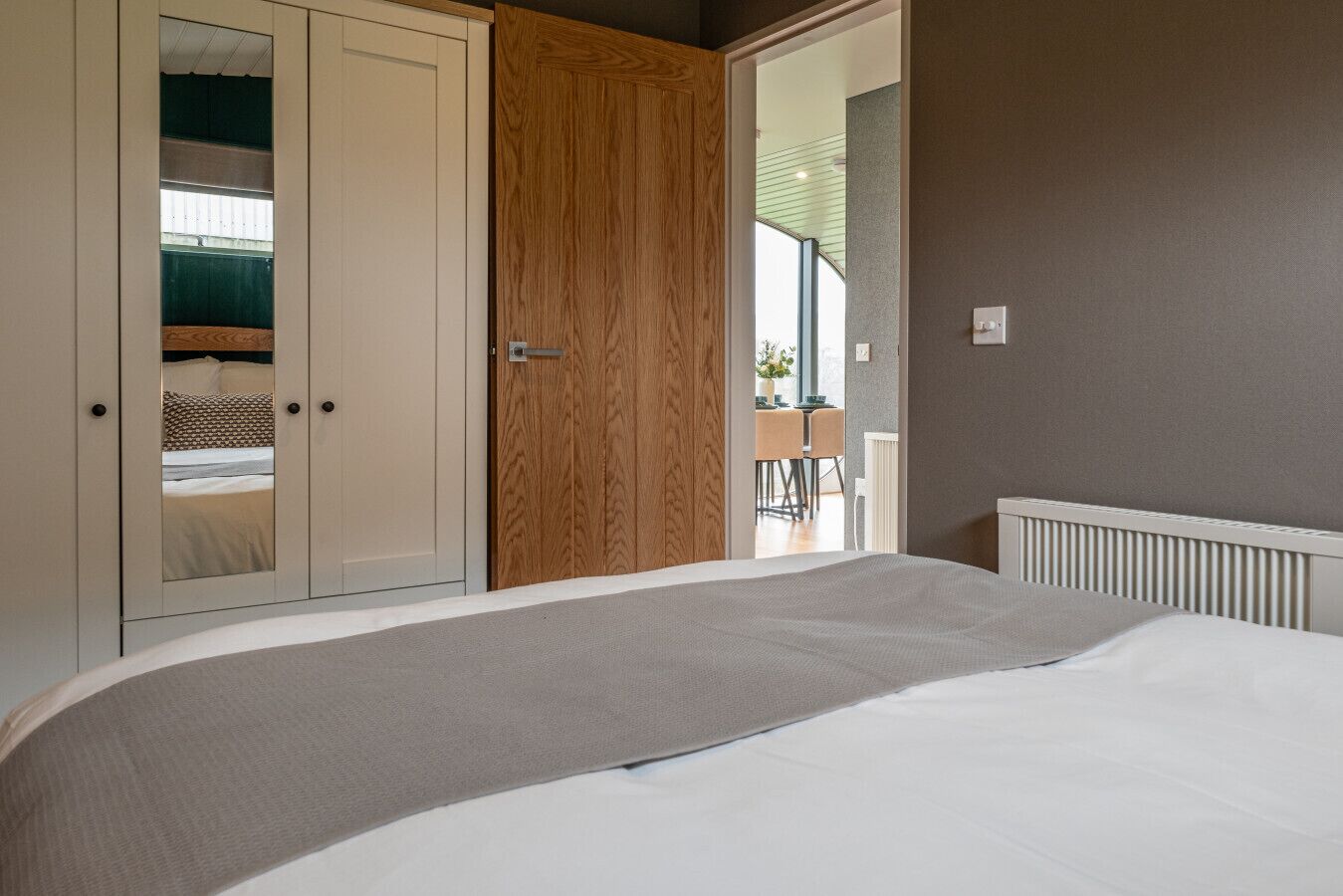 A bedroom with a bed, a wardrobe, and a door leading to a balcony.