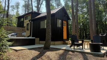 A cabin with a deck, outdoor seating, and a fire pit.