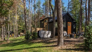 A cabin with a large deck, surrounded by tall trees. - Tiny Home · Hot Tub · Fire Pit · Romantic Escape (Laurelville)